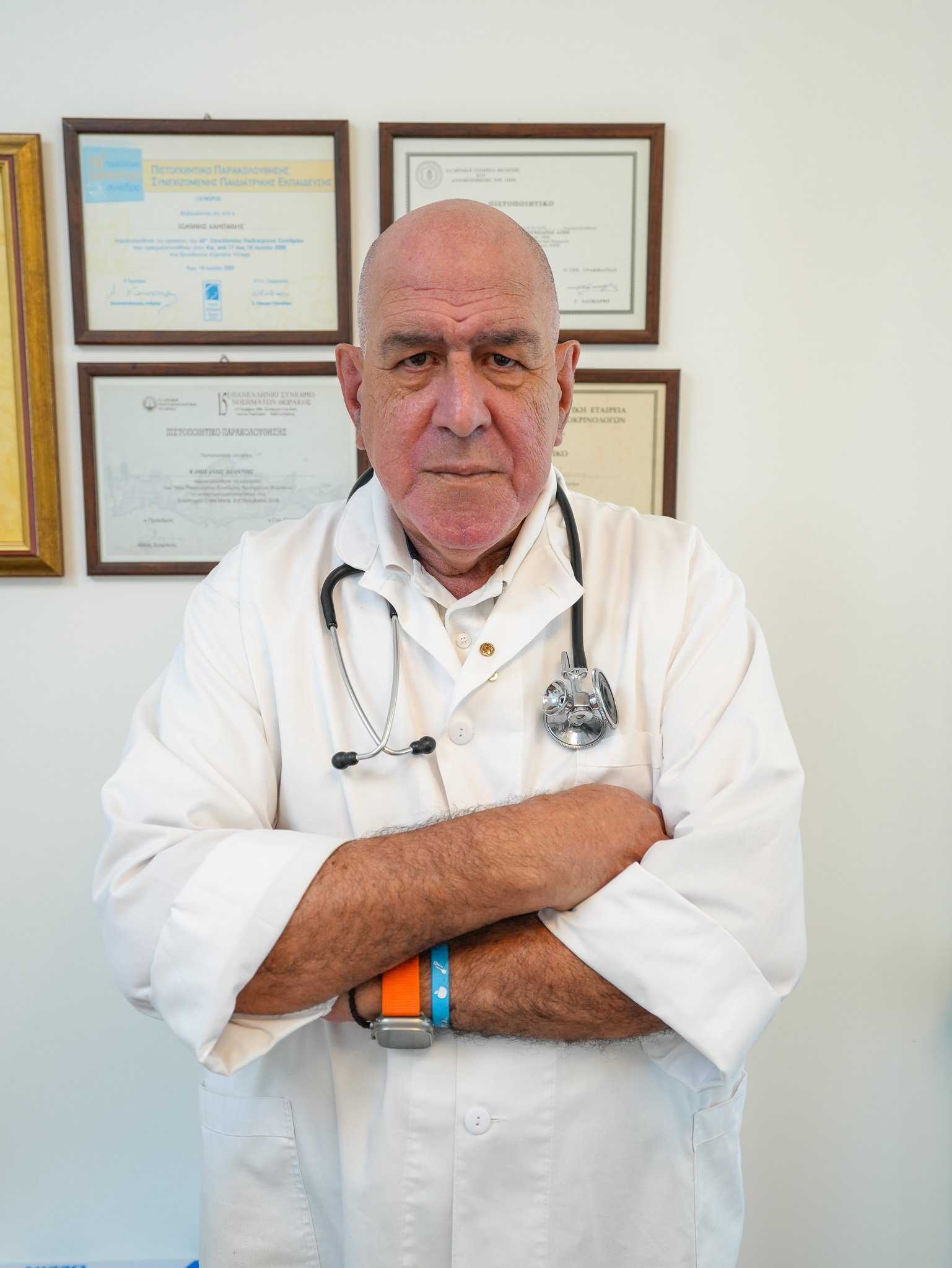 Dr. Ioannis Kambanis in his practice, wearing a white coat and stethoscope