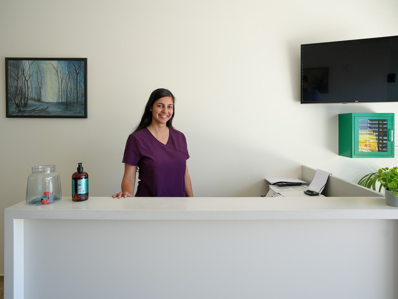 Reception desk staffed by a friendly team member, with a defibrillator on the wall